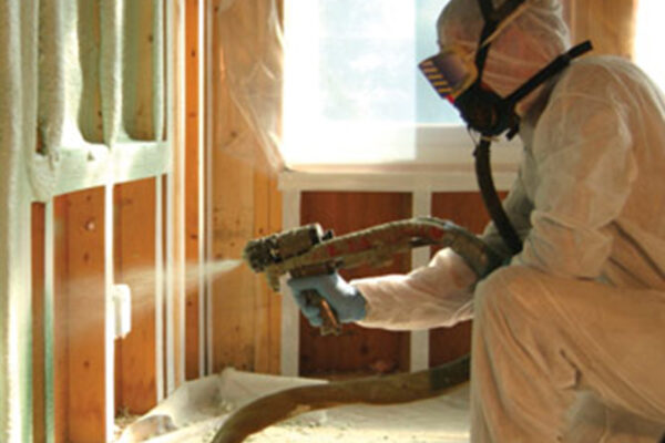 person kneeling, spraying foam in home
