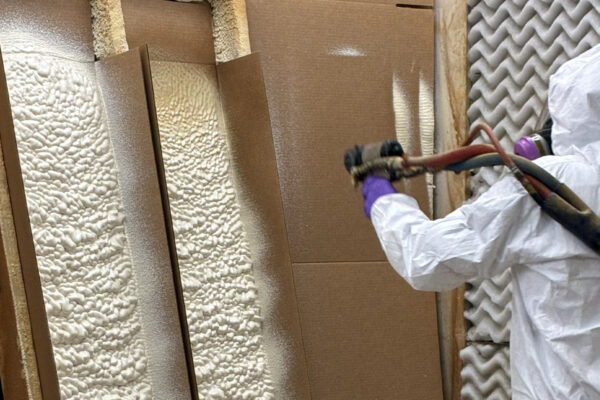 person spraying foam on boards
